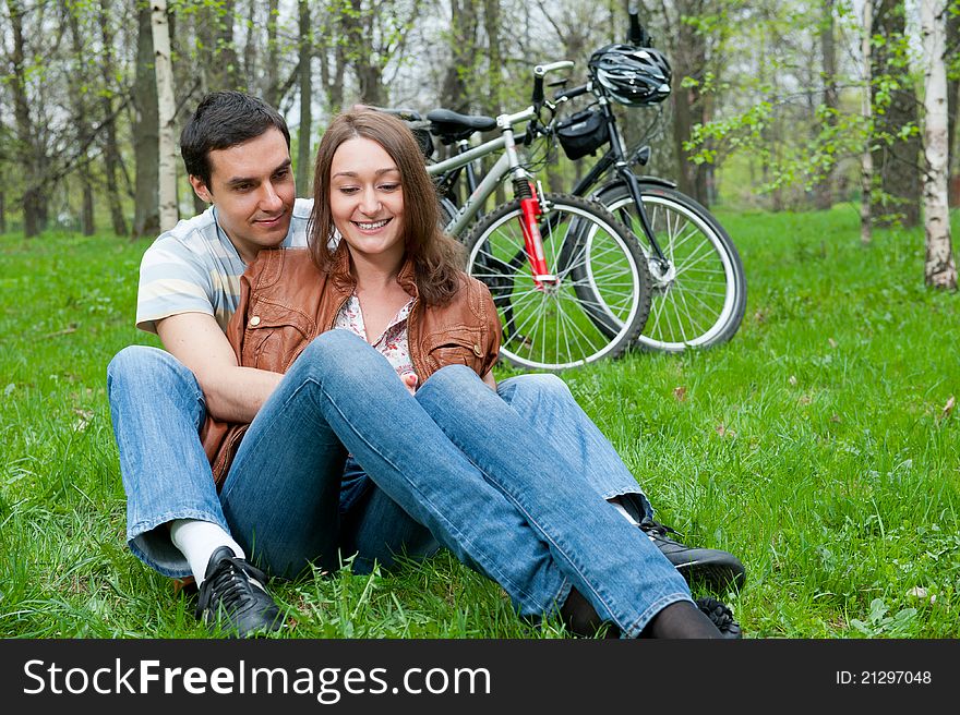 Young couple resting in a park, bicycles on background