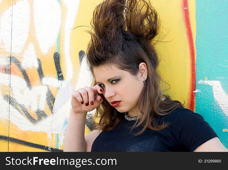 Crying punk girl standing in front of a graffiti wall