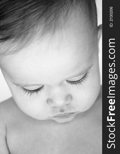 Black and white image of a beautiful baby looking down so his eyelashes are visible. Black and white image of a beautiful baby looking down so his eyelashes are visible