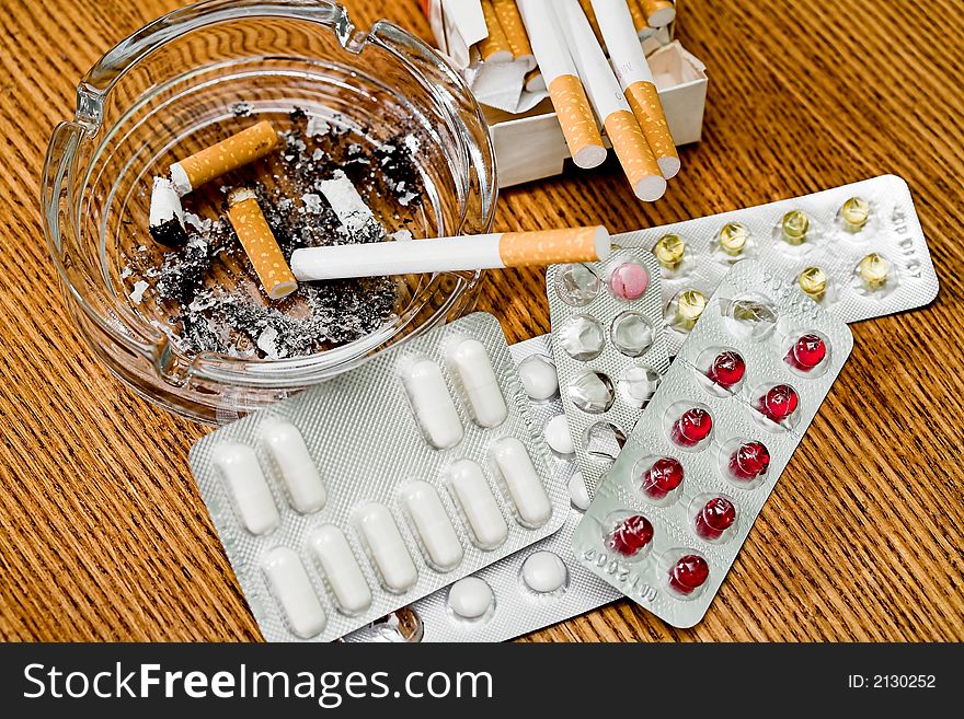 Cigarettes, ashtray, various tablets, stubs on a table, (studio,halogen light). Cigarettes, ashtray, various tablets, stubs on a table, (studio,halogen light).