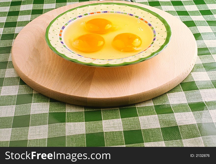 Three broken eggs in a plate on a table