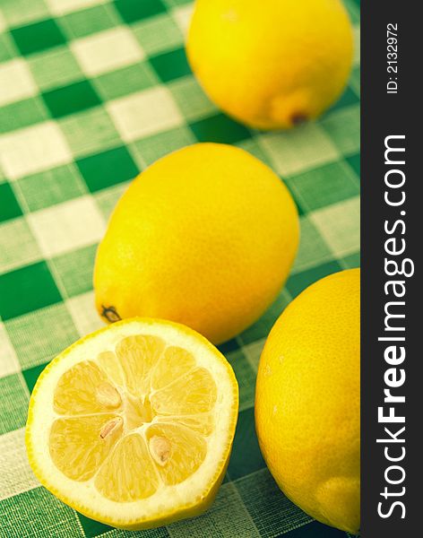 Three whole lemons and slice lay on green cloth. Three whole lemons and slice lay on green cloth