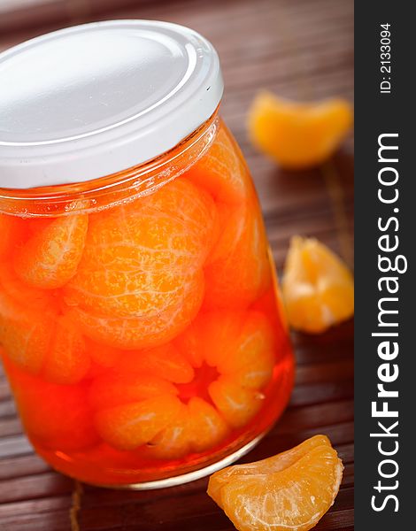 Tangerines liqueur into glass jar on the table