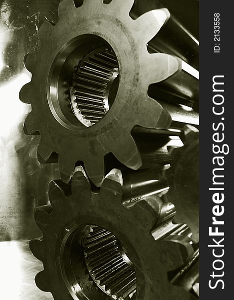 Two gears connecting in bronze-toning against buckled aluminum. Two gears connecting in bronze-toning against buckled aluminum