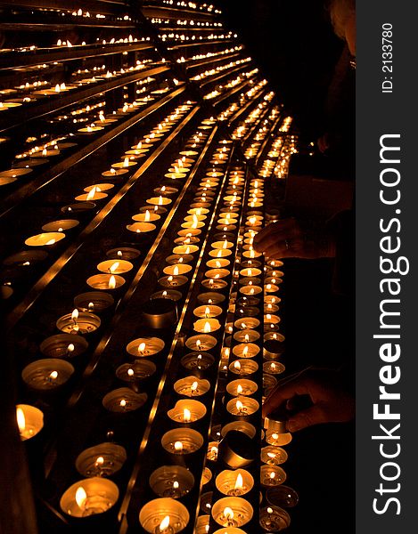 Rows of burning candles inside a cathedral