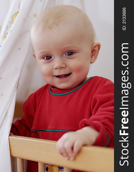 Little boy smiles and stands in baby bed. Little boy smiles and stands in baby bed