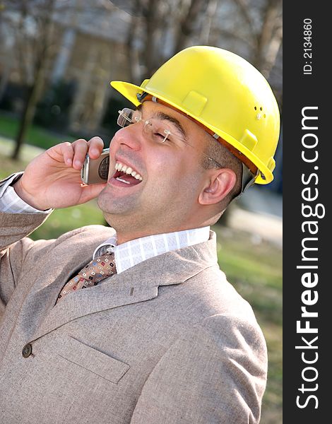 A businessman with helmet calling by mobile phone