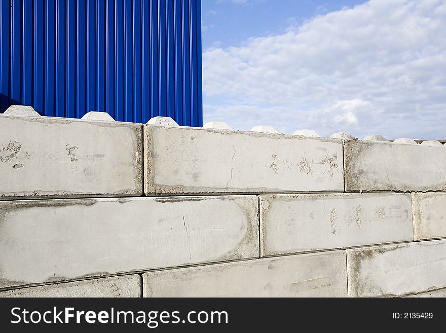 Blue and white industrial buildings including grain or sand silos against blue sky