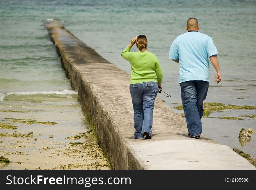 A couple walking on a peer near the sea