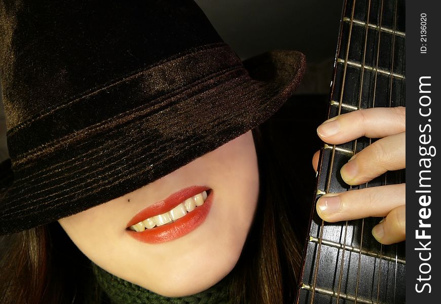 Portrait smiling girl with guitar finger-board, who put she's hat over she's eyes. Portrait smiling girl with guitar finger-board, who put she's hat over she's eyes