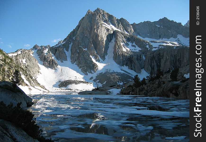 Hungry Packer lake, covered in ice floes, with Mount Haeckel behind under a blue sky with scattered clouds in afternoon light. Hungry Packer lake, covered in ice floes, with Mount Haeckel behind under a blue sky with scattered clouds in afternoon light