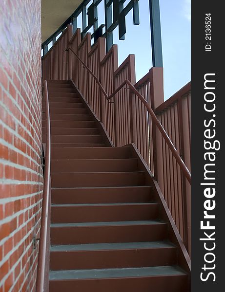 Steep metal staircase leading upward into a large red brick circular building on a bright sunny day. Steep metal staircase leading upward into a large red brick circular building on a bright sunny day.