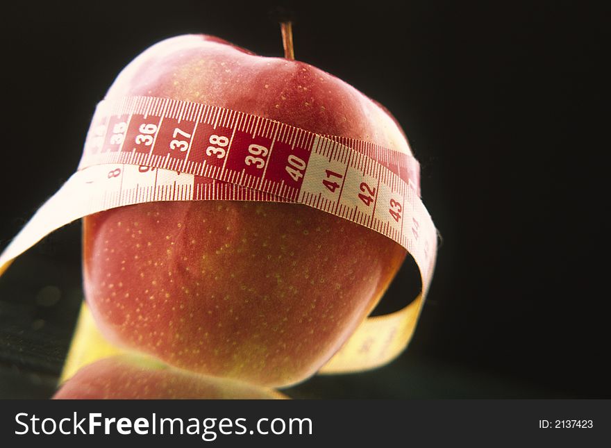 Red apple twisted in measuring meter on  black background