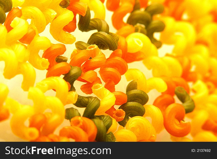 Multi-coloured macaroni products are scattered on  surface of  table