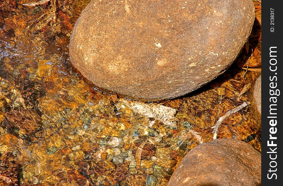 Crystal clear running water coming down from the mountains after rain into a creek showing the peddles and stones on the bottom of the creek bed