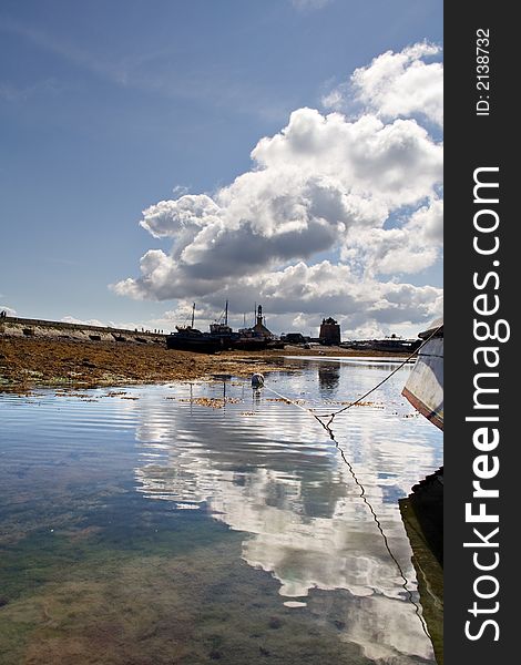 Blue water reflecting the retreating clouds, with old harbor and boat silhouettes. Blue water reflecting the retreating clouds, with old harbor and boat silhouettes