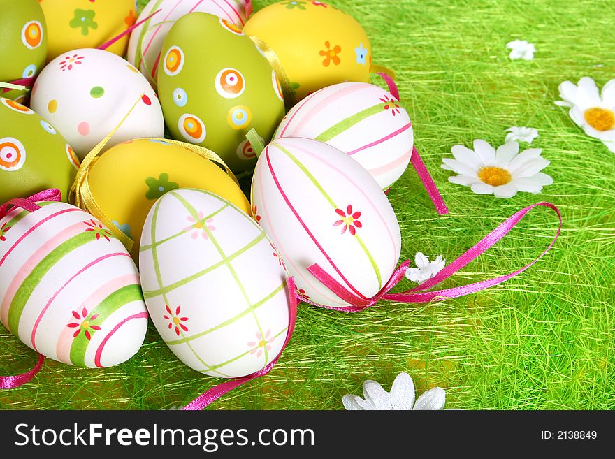 Closeup of several Easter eggs over green grass.