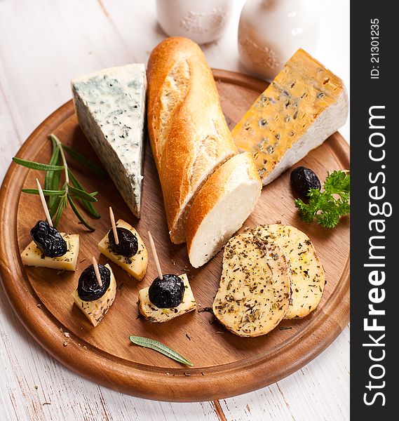 Blue cheese with olives and baguette on kitchen board. Blue cheese with olives and baguette on kitchen board
