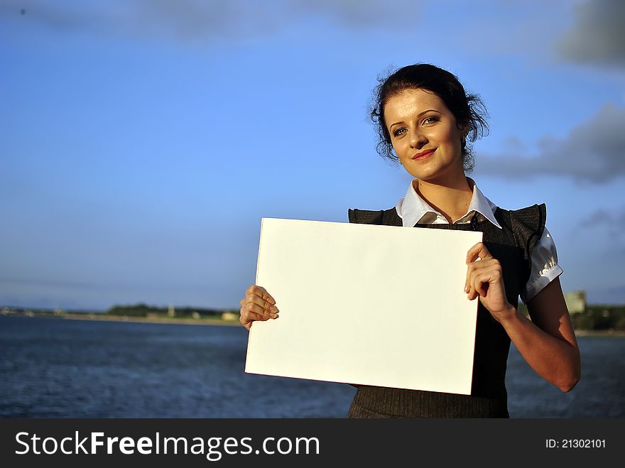 Beautiful girl holding blank paper. sea on the background