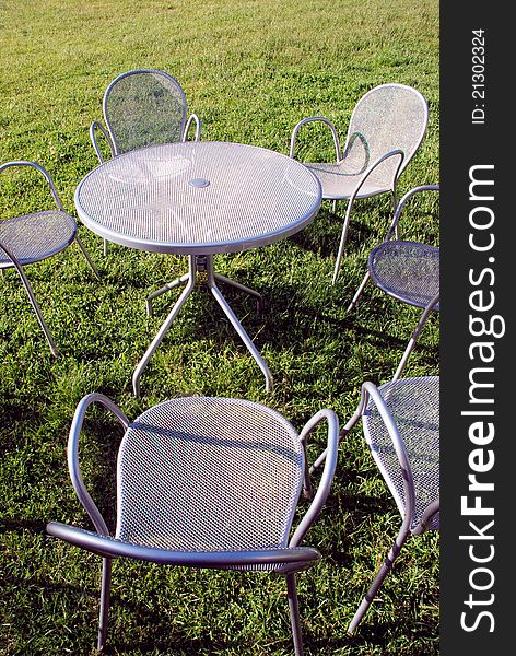 Metal chairs and table on the park grass