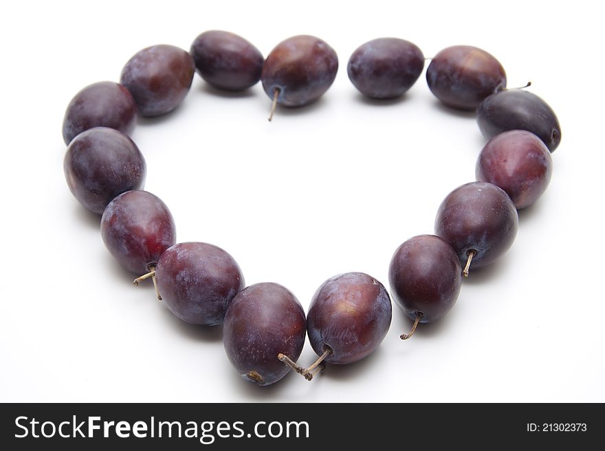 Plums with stem in heart form on white background