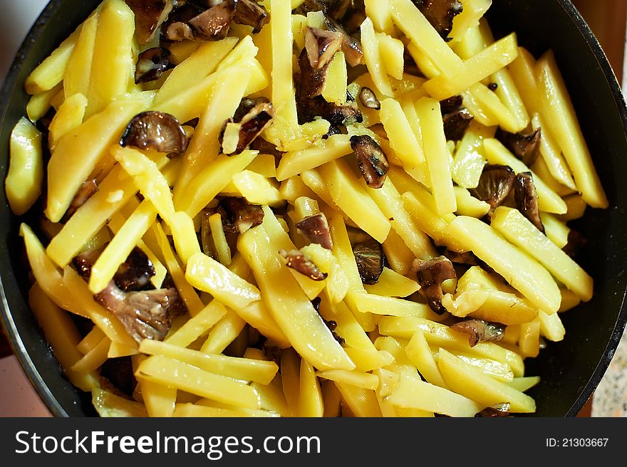 Fried potatoes with mushrooms in a frying pan close-up