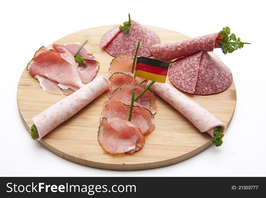 Ham with salami and herbs on wooden plate