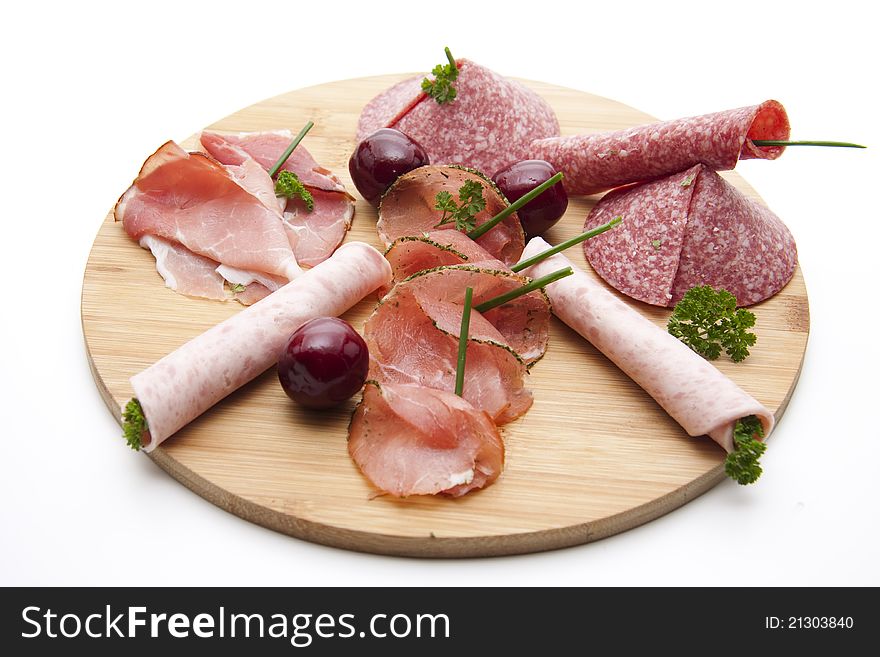 Ham with salami and cherries on wooden plate