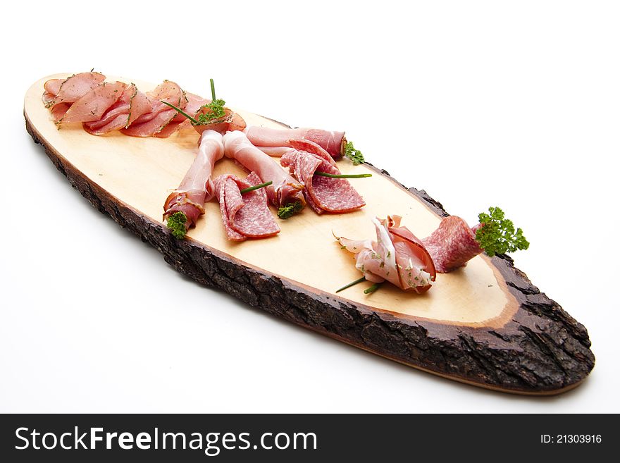 Ham and salamis on wooden board with herbs