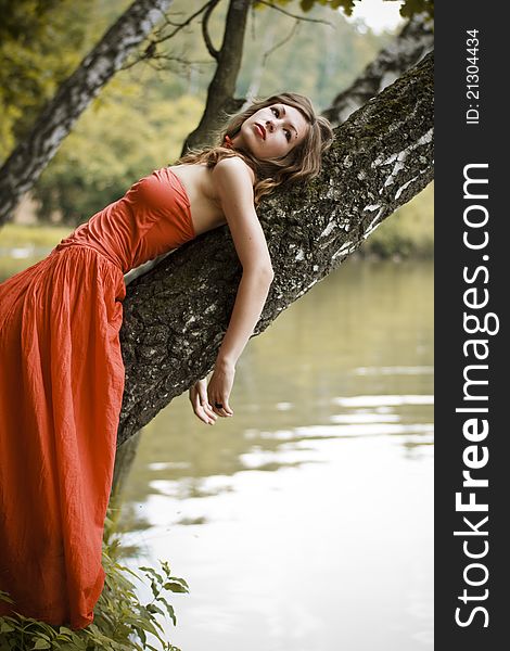 Young woman staying on the bank of the lake. She looks at the sky. Young woman staying on the bank of the lake. She looks at the sky.