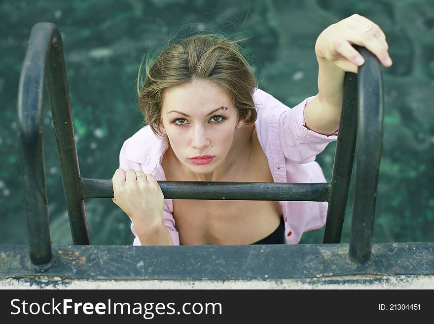 Pretty young woman climbs the stairs to the dock from the water. Pretty young woman climbs the stairs to the dock from the water.