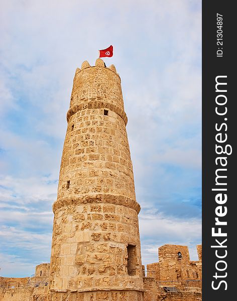 Tower of ribat in Monastir, Tunisia with tunisian flag against cloudy sky. Tower of ribat in Monastir, Tunisia with tunisian flag against cloudy sky