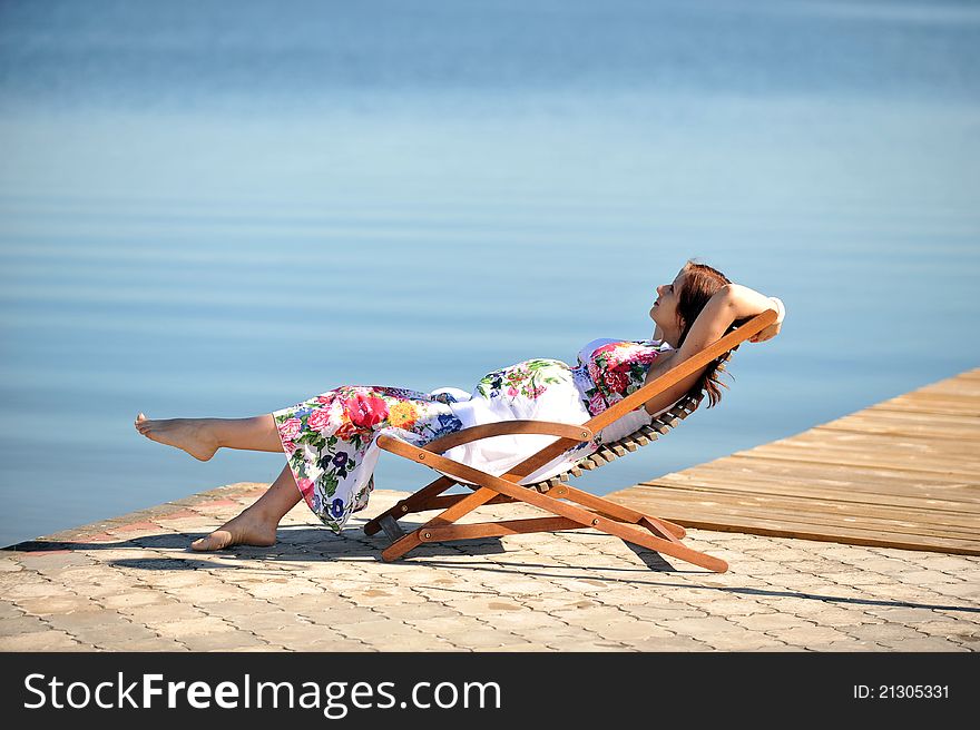 Woman sitting in lounge chair. summer's day on lakeside. Woman sitting in lounge chair. summer's day on lakeside