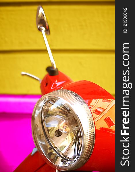 Detail of red moped with rearview mirror and headlight