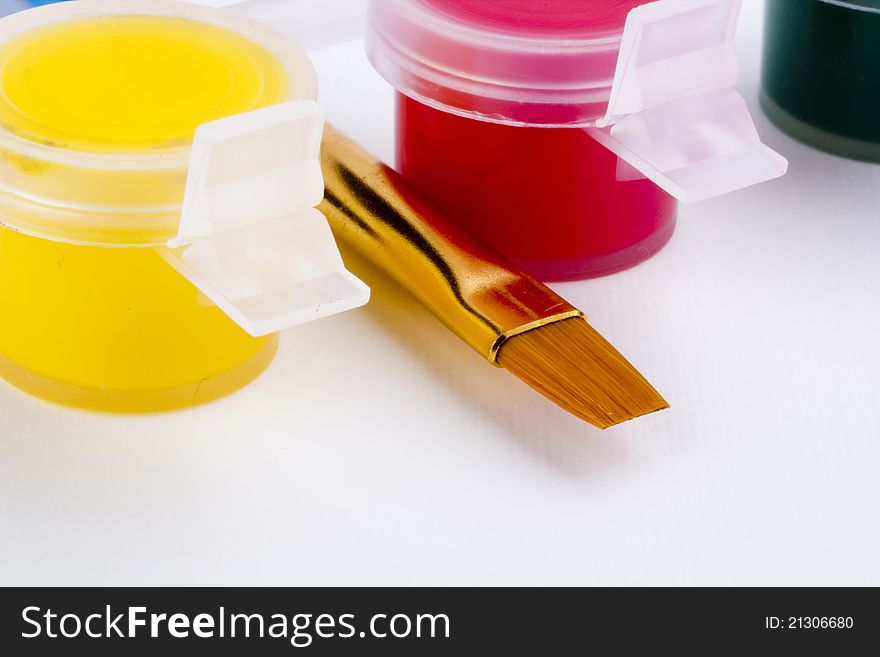 Flat art brush laying between containers with red and yellow paint. Flat art brush laying between containers with red and yellow paint.