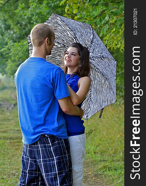 Couple in farm field with arms around each other holding an umbrella. Couple in farm field with arms around each other holding an umbrella