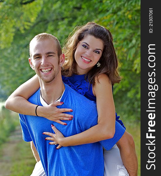 Couple in a piggy - back embrace smiling at camera