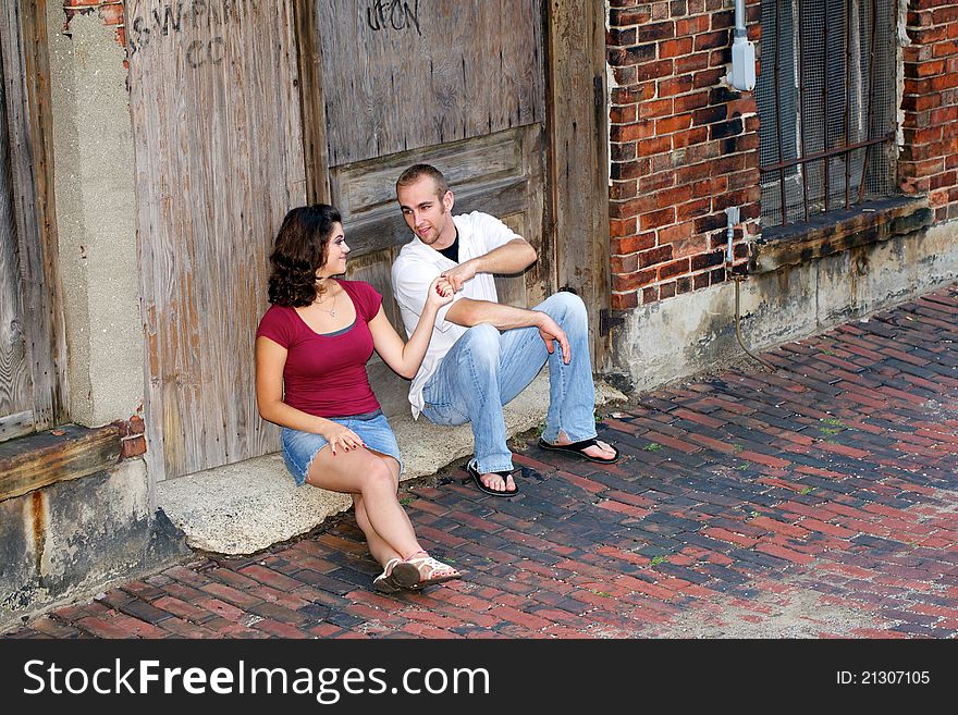Couple sitting in front of old building enjoying each others company. Couple sitting in front of old building enjoying each others company