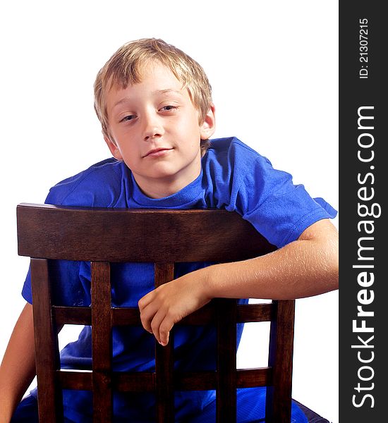 Young boy leaning on a chair with a smirk on his face. Young boy leaning on a chair with a smirk on his face