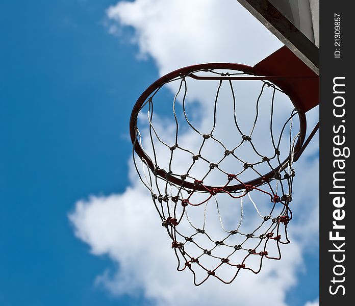 Basketball basket against pines and blue sky.