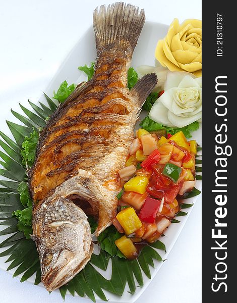 Close up view of nice fried fish with vegetables on white back