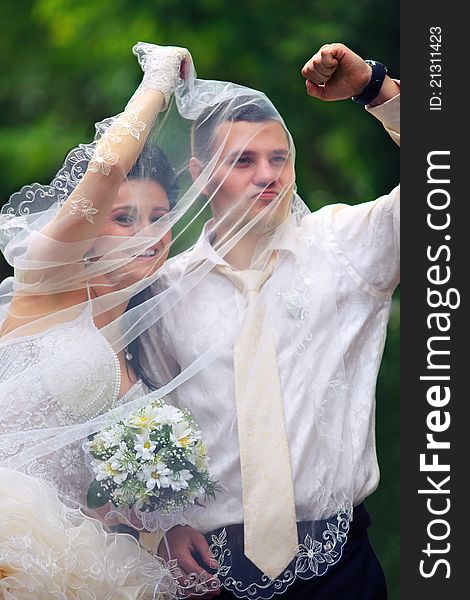 Portait of young wedding couple under veil