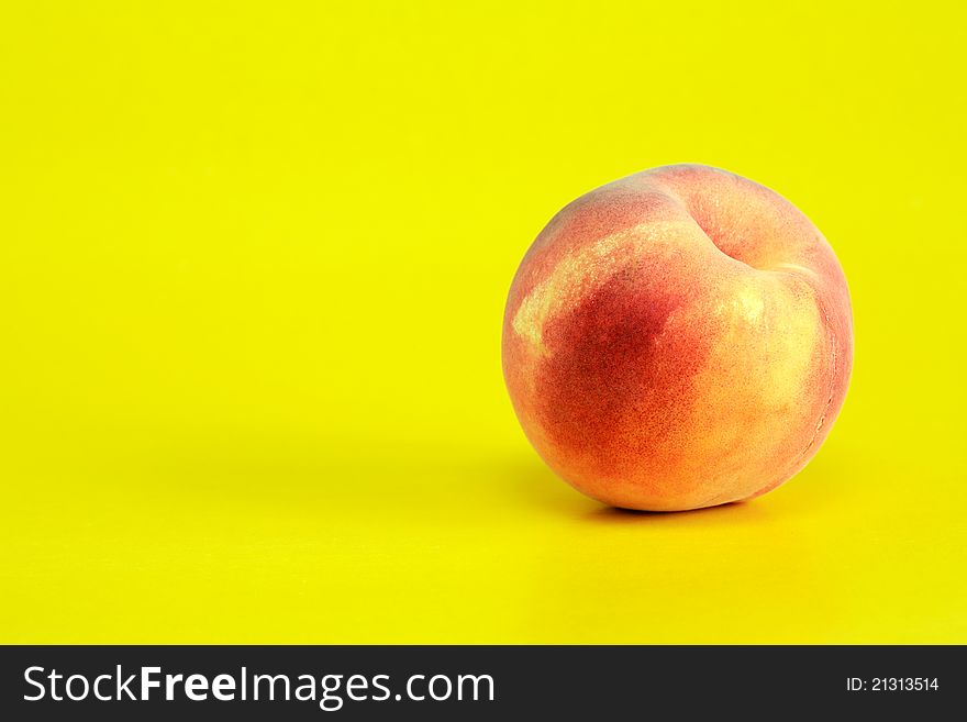 One peach fruit on yellow background with free space for text. One peach fruit on yellow background with free space for text