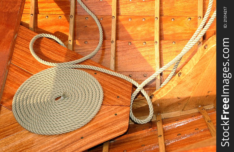 Coiled rope on teak deck. Decorative coiling is called 'cheesing' or 'flemish coil' and was used to help rope dry. Coiled rope on teak deck. Decorative coiling is called 'cheesing' or 'flemish coil' and was used to help rope dry.