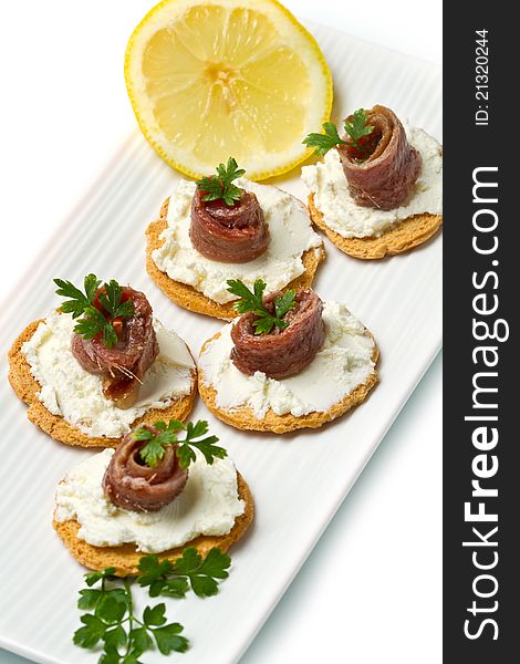 Canapes with anchovy on white dish