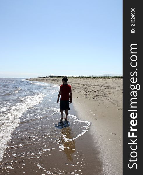 Boy walking alone on a beach. Boy walking alone on a beach.