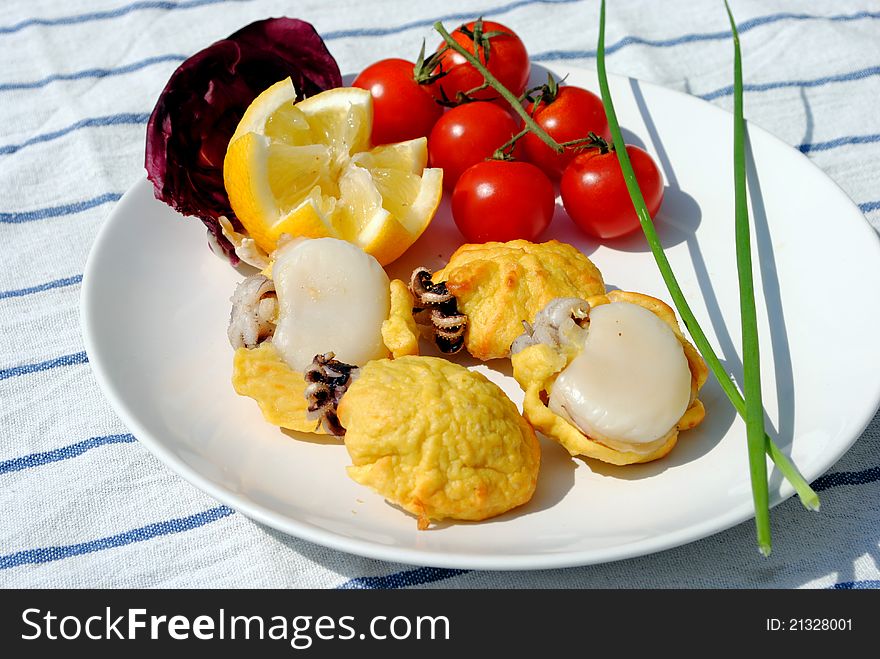 Stuffed cuttlefish in white dish whit tomatoes and lemon over striped tablecloth