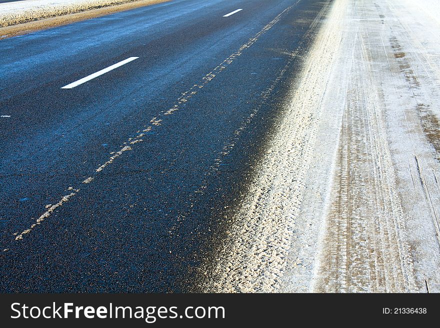 Part of the asphalted road to a winter season (on road traces from passing cars). Part of the asphalted road to a winter season (on road traces from passing cars)