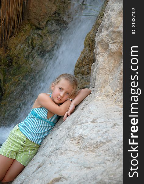 Child girl on the background of a waterfall poses woman