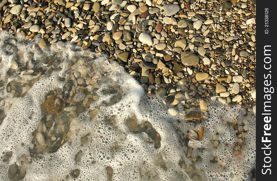 Sea waves lapping on the pebbles in the rays of the rising summer sun. Sea waves lapping on the pebbles in the rays of the rising summer sun